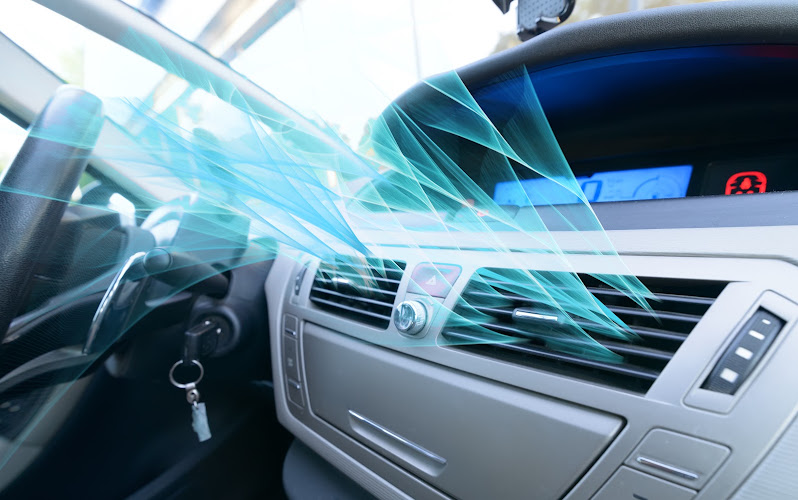 Car dashboard air vents blowing chilled air, illustrating automotive air conditioning performance
